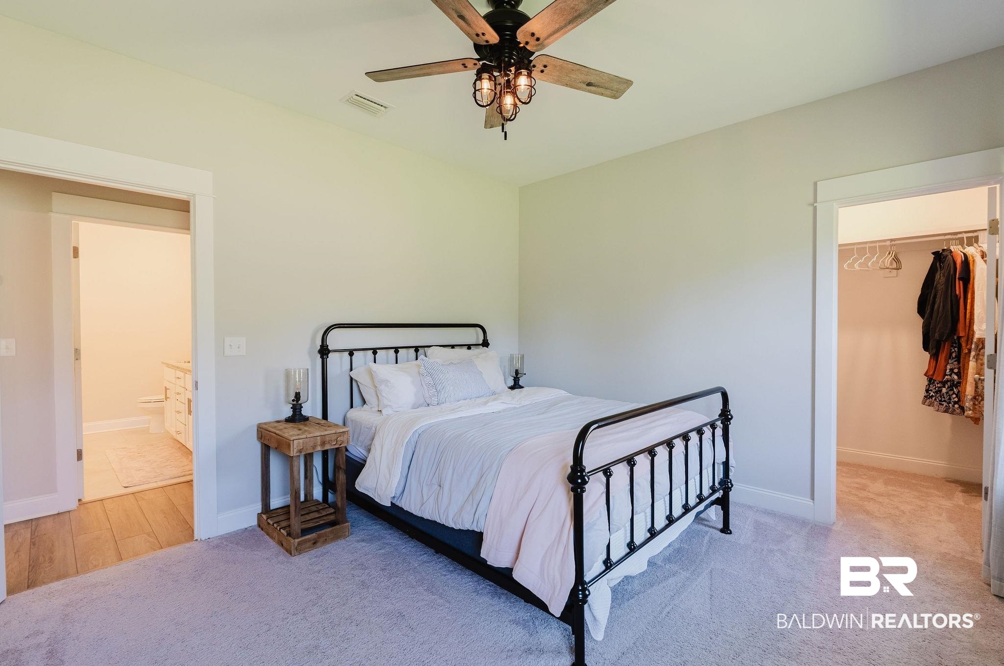 7872 Calverton Street Foley, AL 36535 - Photo 49 of 76 Carpeted bedroom featuring a decorative ceiling fan with lighting, light-toned walls, and an open doorway revealing a bathroom with wood-finish flooring and a white vanity