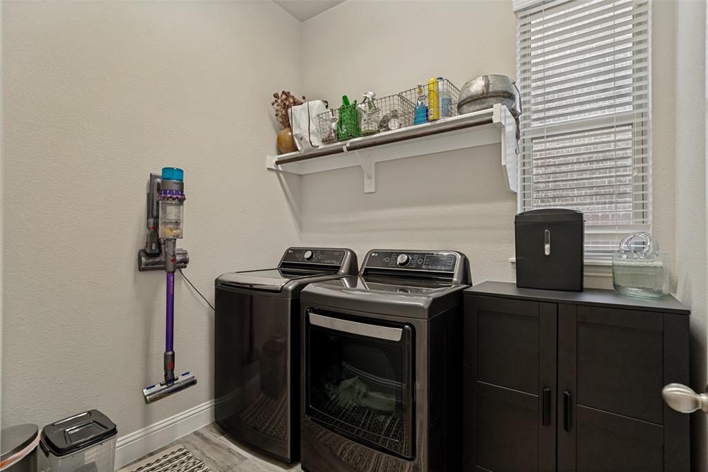 14948 Gentry Drive Aledo, TX 76008 - Photo 23 of 25 Laundry area featuring a side-by-side washer and dryer, a built-in white shelf, a window with horizontal blinds, and wood-finish flooring