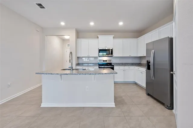 a kitchen with kitchen island a white cabinets and refrigerator
