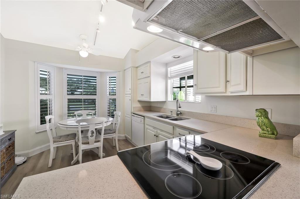 15350 Wimborne Lane, Unit 2 Naples, FL 34110 - Photo 10 of 42 a kitchen with stainless steel appliances granite countertop a stove a sink a dining table and chairs with wooden floor