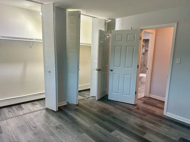 an empty room with wooden floor and closet area