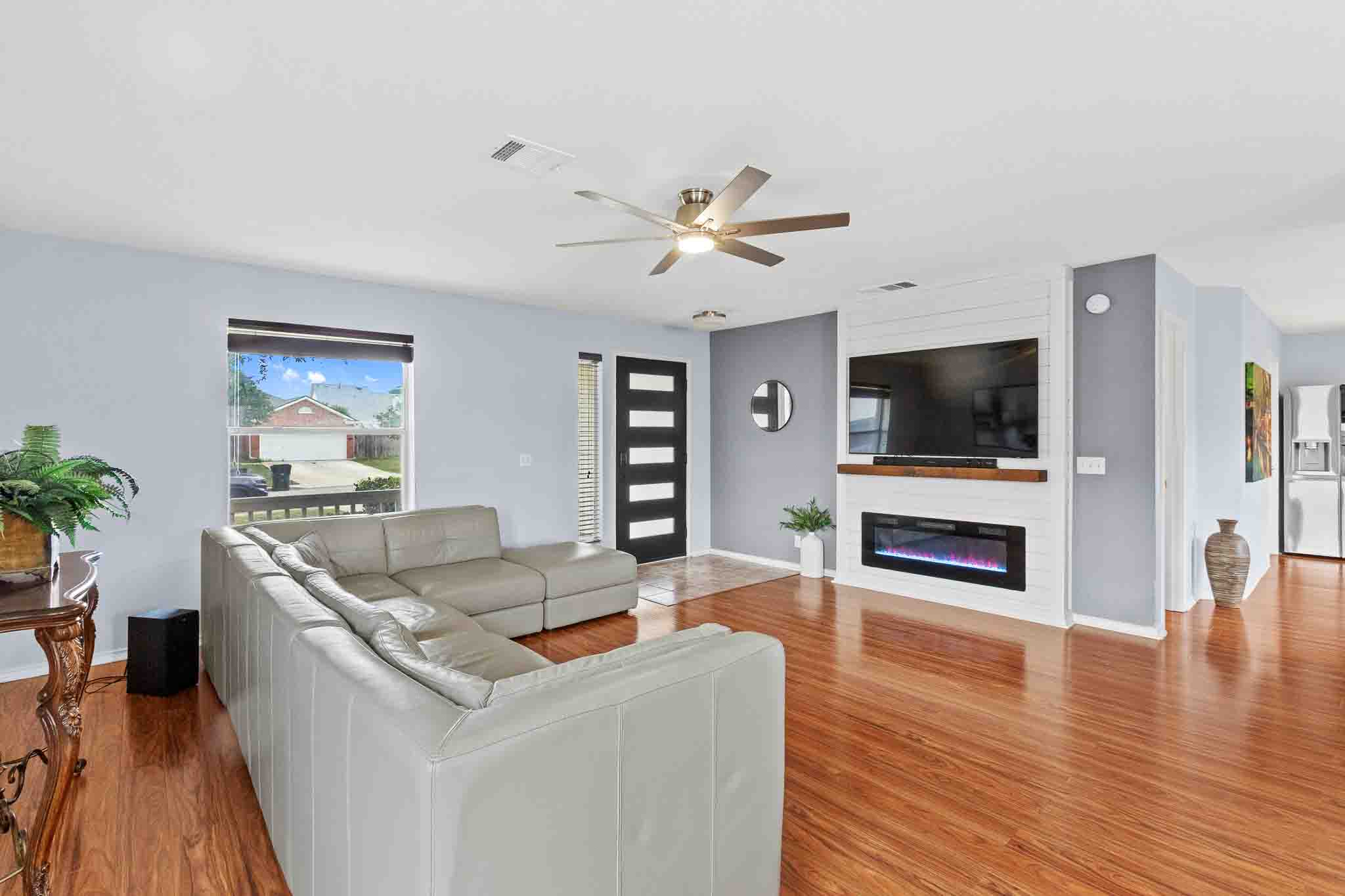 270 Endeavour Kyle, TX 78640 - Photo 2 of 20 The living area features hardwood floors, a ceiling fan, and a modern fireplace with a shiplap accent wall