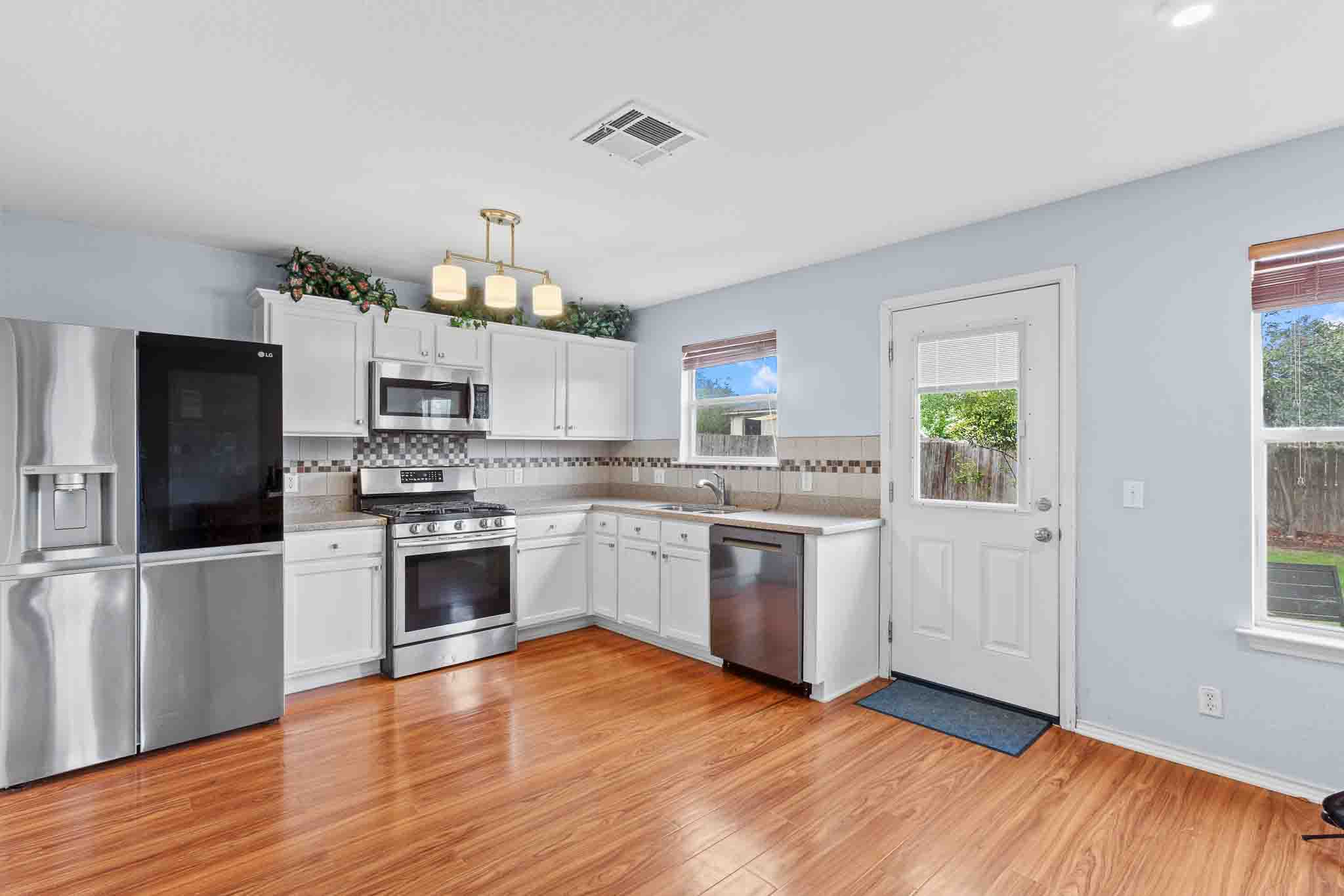 270 Endeavour Kyle, TX 78640 - Photo 5 of 20 The kitchen features wood flooring, white cabinetry, stainless steel appliances, and light-colored countertops