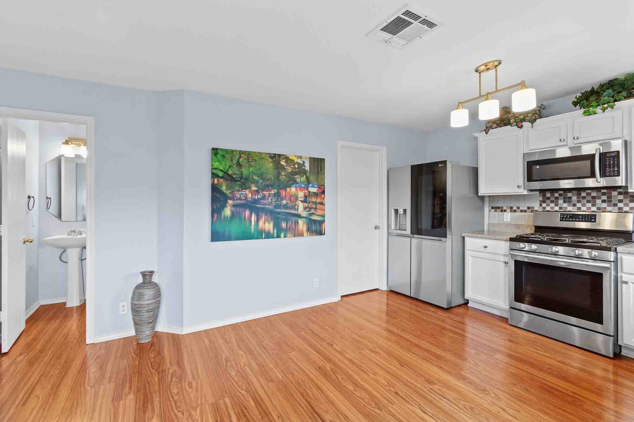 270 Endeavour Kyle, TX 78640 - Photo 7 of 20 This property features wood flooring, light blue walls, and a kitchen with white cabinetry, stainless steel appliances, and a tiled backsplash