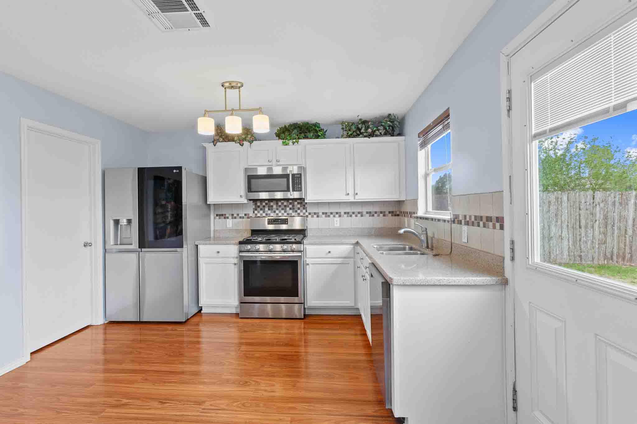 270 Endeavour Kyle, TX 78640 - Photo 8 of 20 The kitchen features wood flooring, white cabinetry, stainless steel appliances, and a tiled backsplash