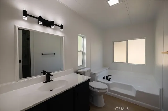 a bathroom with a bathtub sink mirror vanity and toilet
