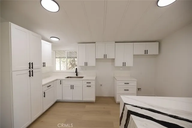 a kitchen with white cabinets and sink