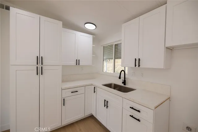 a kitchen with white cabinets and sink