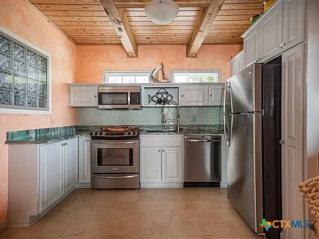 a kitchen with stainless steel appliances granite countertop a refrigerator and a stove