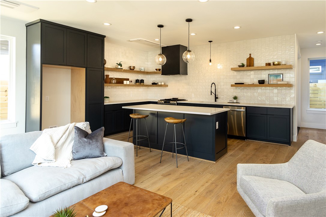 a kitchen with stainless steel appliances granite countertop a stove a sink dishwasher a refrigerator and a dining table with wooden floor