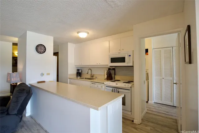 a open kitchen with stainless steel appliances granite countertop a stove top oven a refrigerator a sink and dishwasher with white cabinets