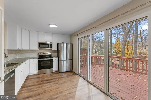 a kitchen with stainless steel appliances granite countertop a refrigerator a stove top oven a sink and dishwasher with wooden floor