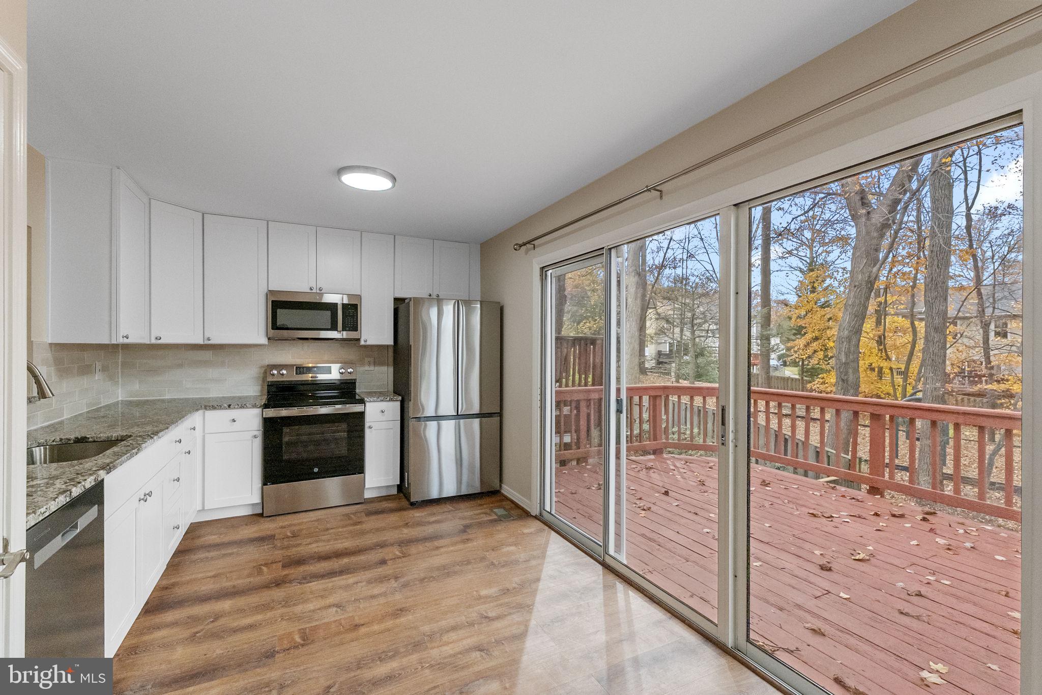 4 Waterside Court Germantown, MD 20874 - Photo 9 of 37 a kitchen with stainless steel appliances granite countertop a refrigerator a stove top oven a sink and dishwasher with wooden floor