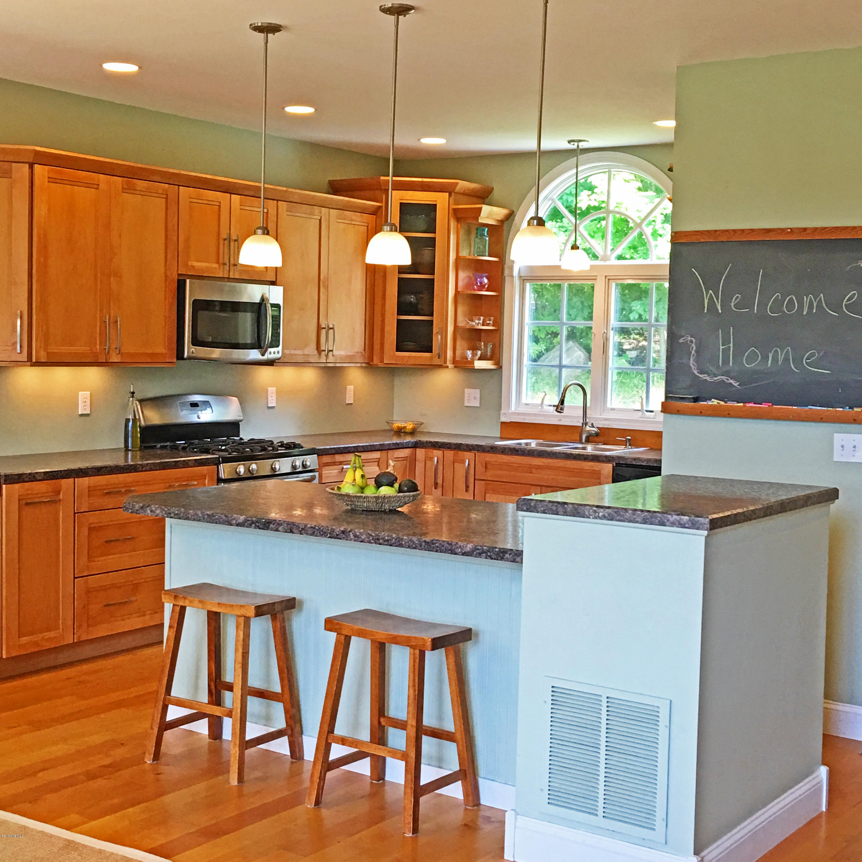 93 Stebbins Road Otis, MA 01253 - Photo 10 of 41 a kitchen with stainless steel appliances granite countertop a stove top oven a sink a dining table and chairs with wooden floor