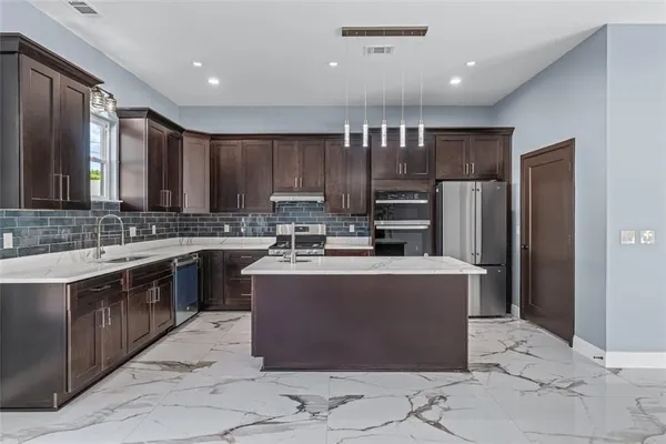 a kitchen with kitchen island a counter top space cabinets and stainless steel appliances