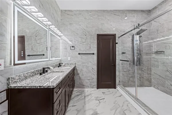 a bathroom with a granite countertop sink a large mirror and a shower