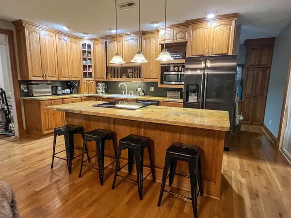 a kitchen with stainless steel appliances granite countertop table chairs sink refrigerator and microwave