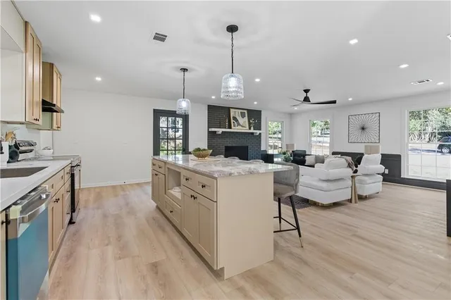 a large white kitchen with stainless steel appliances granite countertop a stove oven a sink dishwasher and white cabinets with wooden floor