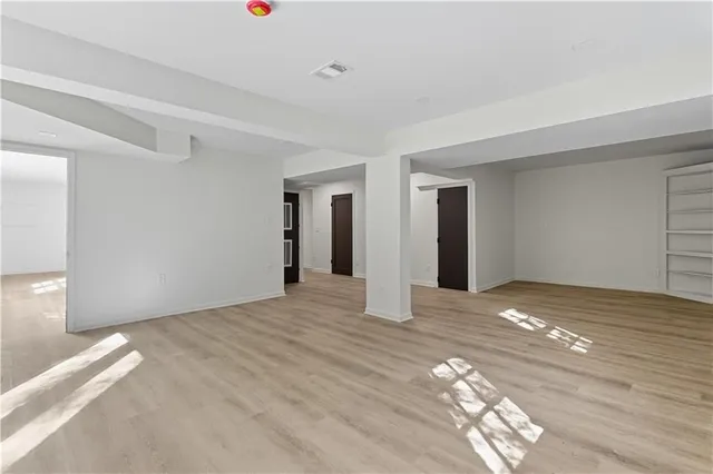 an empty room with wooden floor fan and windows