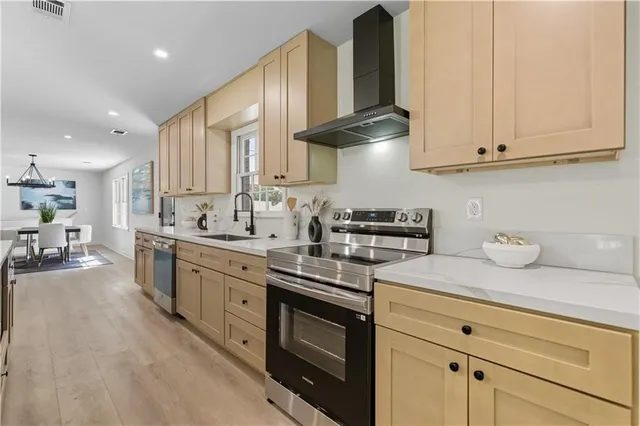 a kitchen with stainless steel appliances granite countertop a sink a stove and cabinets