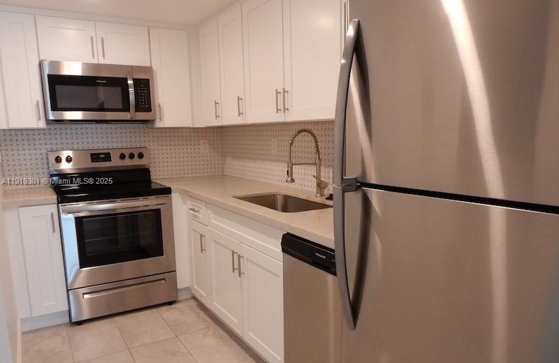 400 North Surf Road, Unit 303 Hollywood, FL 33019 - Photo 2 of 17 a kitchen with stainless steel appliances a refrigerator sink and microwave