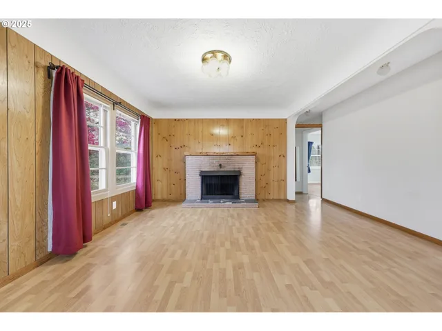 a view of an empty room with a fireplace and a window