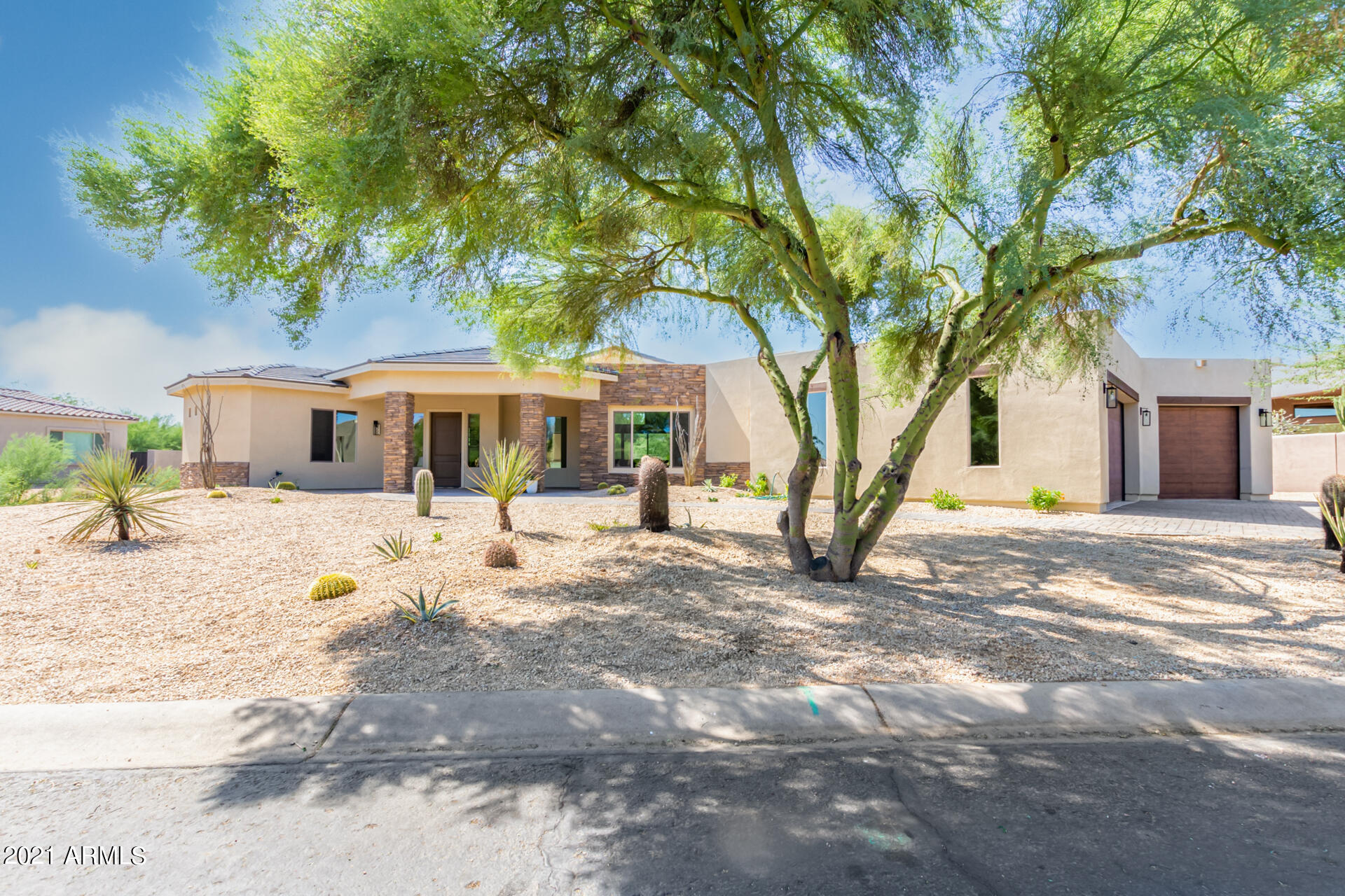 a front view of a house with a dirt yard and a large tree