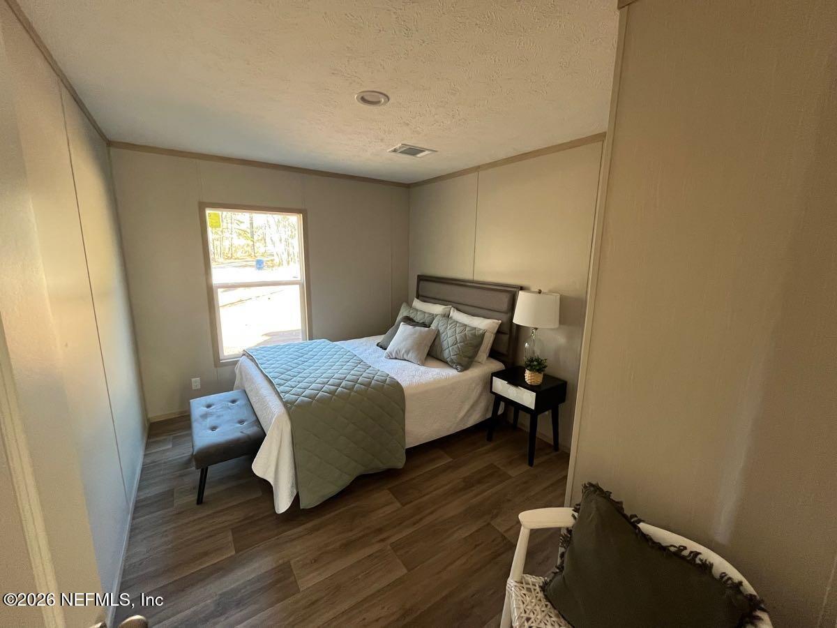 28711 Tracy Road Hilliard, FL 32046 - Photo 17 of 33 a bedroom with a bed and wooden floor