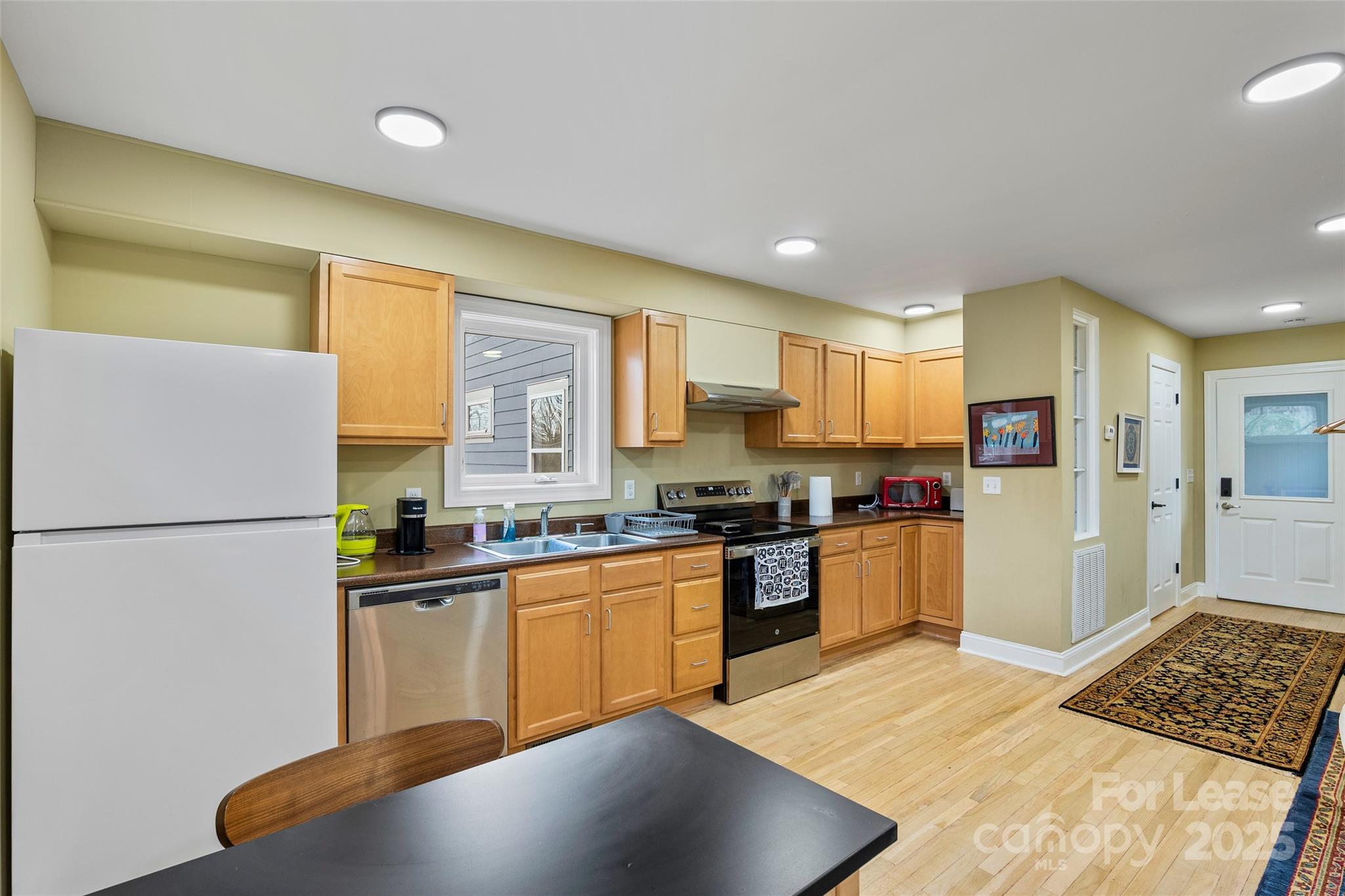 5 Elmore Street Asheville, NC 28804 - Photo 26 of 37 a kitchen with stainless steel appliances granite countertop a refrigerator a sink dishwasher a stove with wooden cabinets and floor