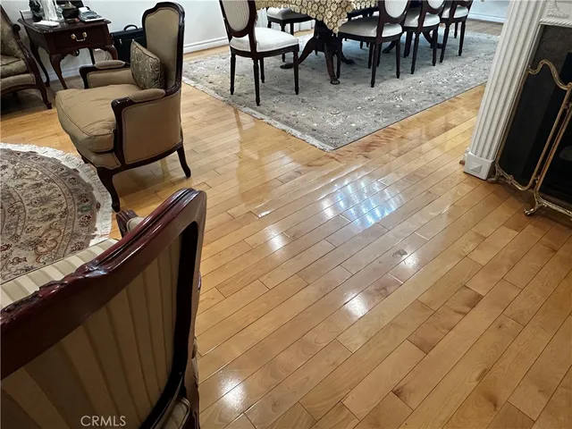 a living room with couches and a dining table with wooden floor