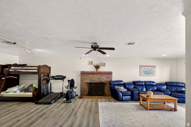 161 West 950 South, Unit Q1 St. George, UT 84770 - Photo 24 of 37 Living room with light wood-style floors, a textured ceiling, a brick fireplace, and a ceiling fan