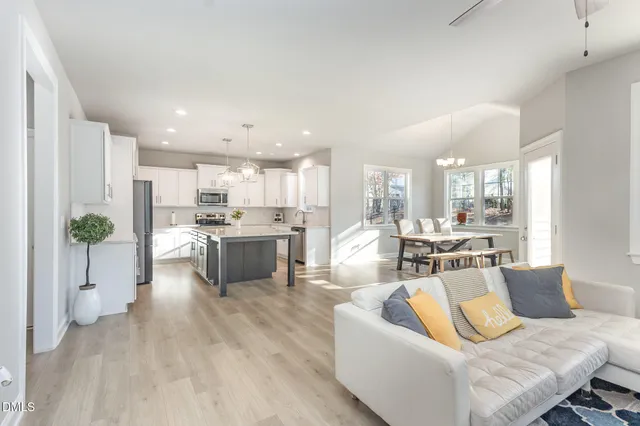 a living room with furniture white walls and kitchen view
