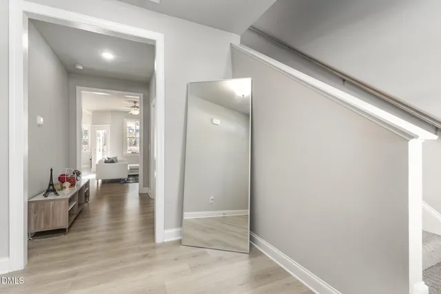 a view of a hallway with wooden floor and a living room