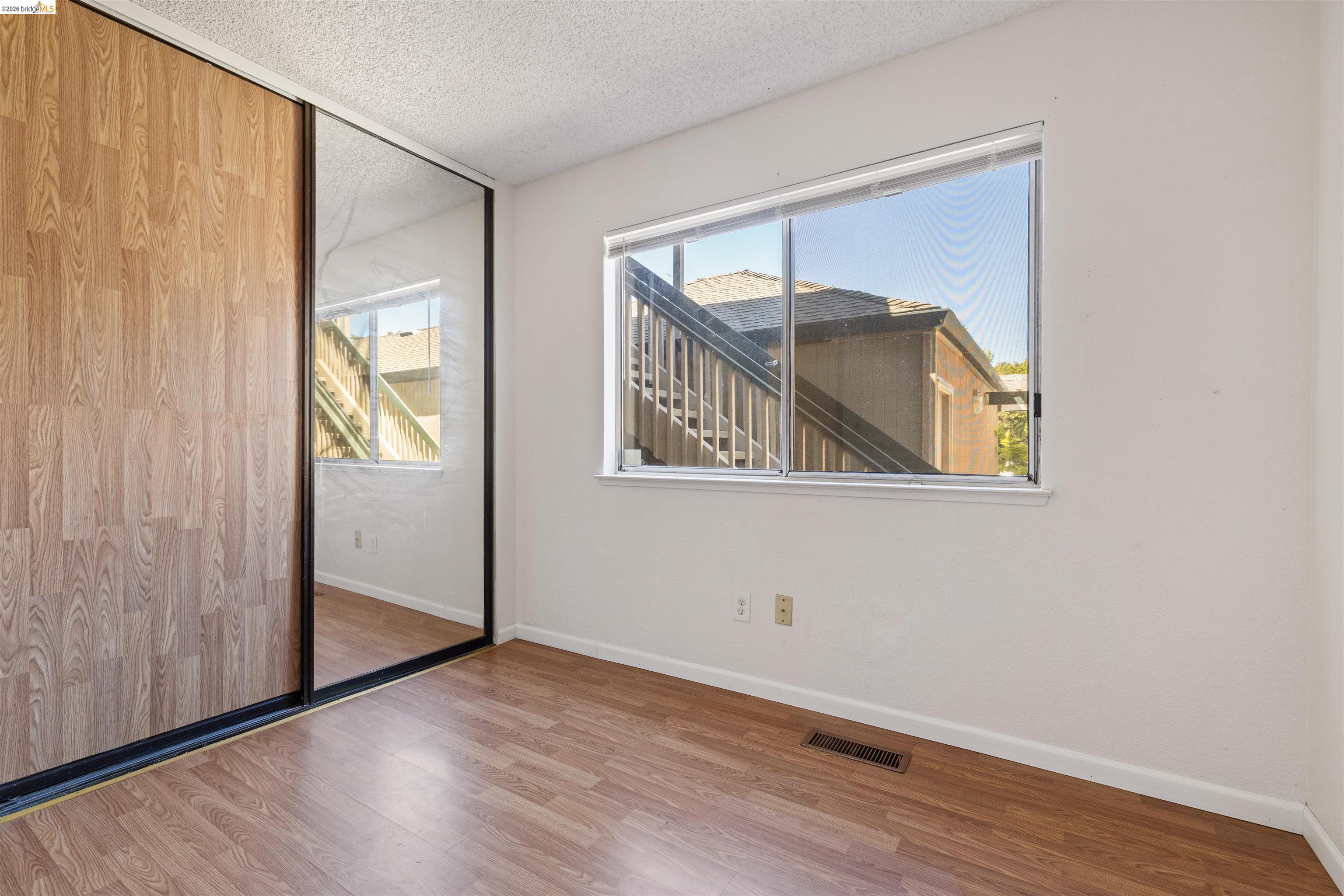1151 Chadwick Circle Bay Point, CA 94565 - Photo 12 of 23 Bedroom featuring wood-finish flooring, a large window, and mirrored closet doors