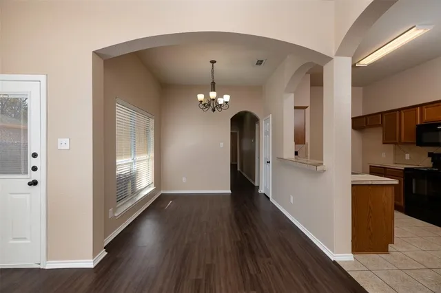 a view of a hallway with wooden floor and a kitchen