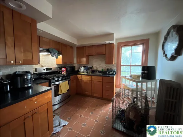 a kitchen with stainless steel appliances granite countertop a stove a sink and a microwave