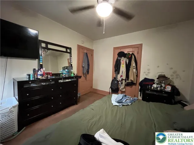 a bedroom with a bed and a flat tv screen on dresser