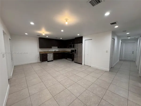 an empty room with kitchen and natural light