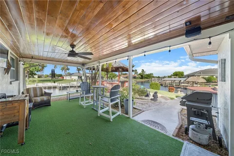 a view of a patio with table and chairs and a barbeque grill with a yard