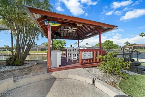 a view of a patio with table and chairs under an umbrella with palm trees