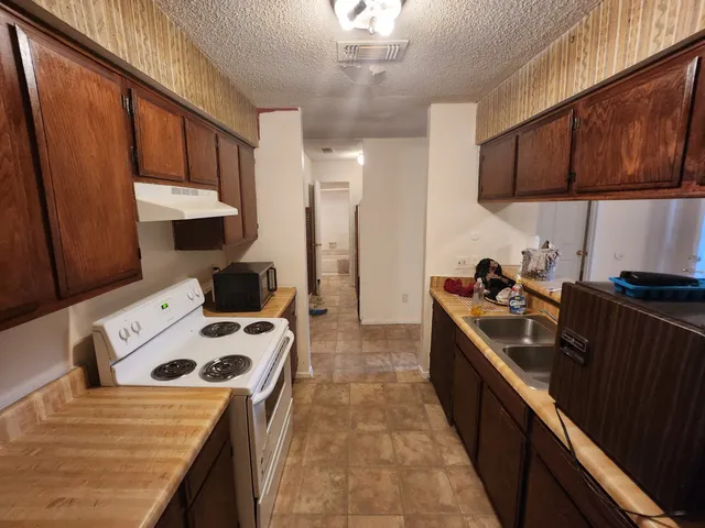 a kitchen with stainless steel appliances a stove a sink dishwasher and wooden cabinets with wooden floor