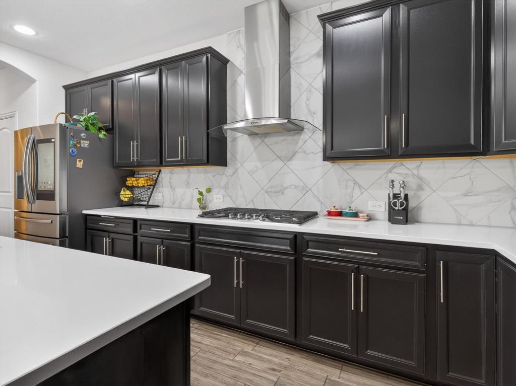 636 Corner Post Path Celina, TX 75009 - Photo 12 of 40 Kitchen featuring dark wood cabinetry, light-toned countertops, a stainless steel range hood, a gas cooktop, and a diagonal tile backsplash