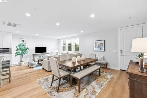 a kitchen with stainless steel appliances granite countertop a stove a refrigerator a sink a dining table and chairs with wooden floor