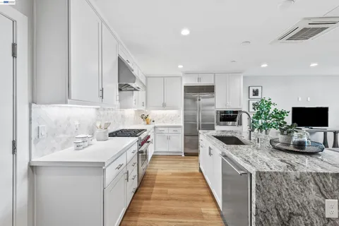 a kitchen with stainless steel appliances a white stove top oven a sink a dishwasher a refrigerator and white cabinets