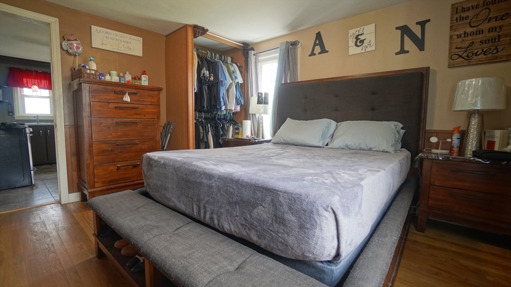 41 Parallel Street Springfield, MA 01104 - Photo 21 of 35 a large bed sitting in a bedroom next to a lamp on a dresser and a wooden floor