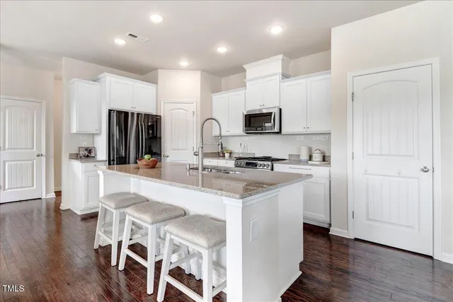 a kitchen with kitchen island white cabinets and stainless steel appliances