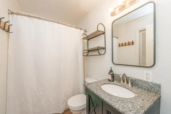 a bathroom with a granite countertop sink mirror vanity and toilet