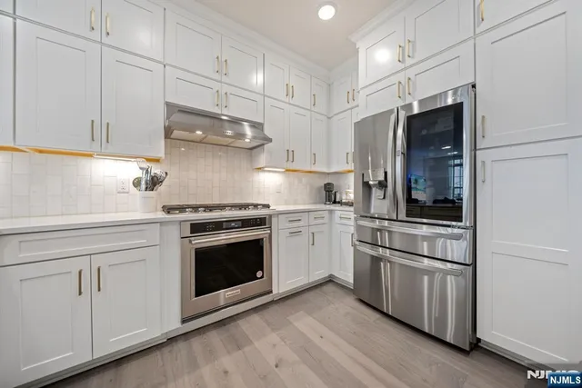 a kitchen with granite countertop white cabinets and stainless steel appliances