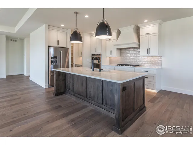 a kitchen with stainless steel appliances granite countertop a sink a stove a refrigerator and island