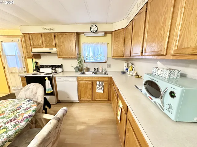 a kitchen with stainless steel appliances a sink a stove a refrigerator cabinets and a window